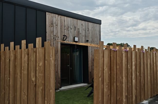 Entrée du Gîte D avec son enseigne et sa terrasse en gazon synthétique